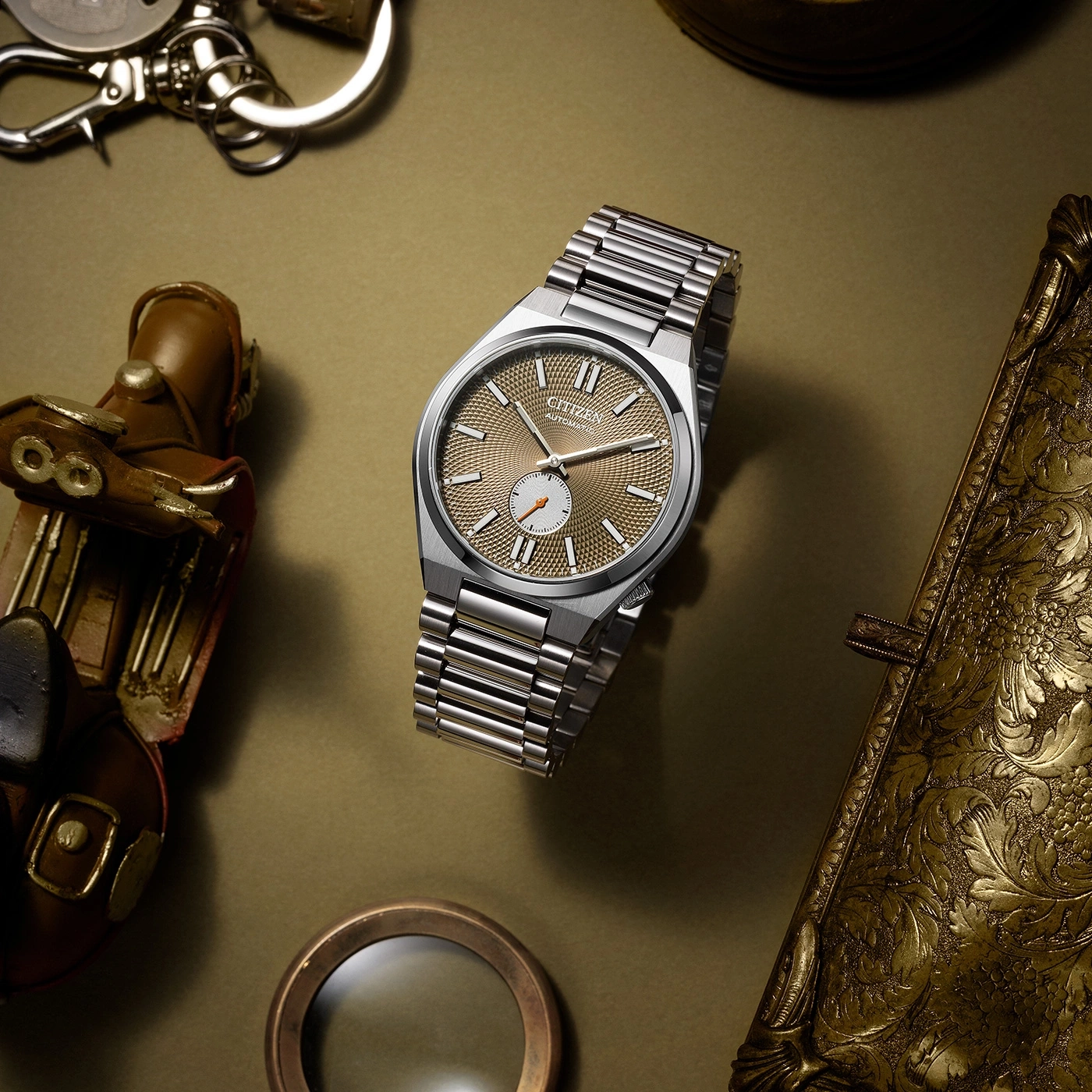 Citizen horloge met gouden wijzerplaat, omringd door vintage accessoires.