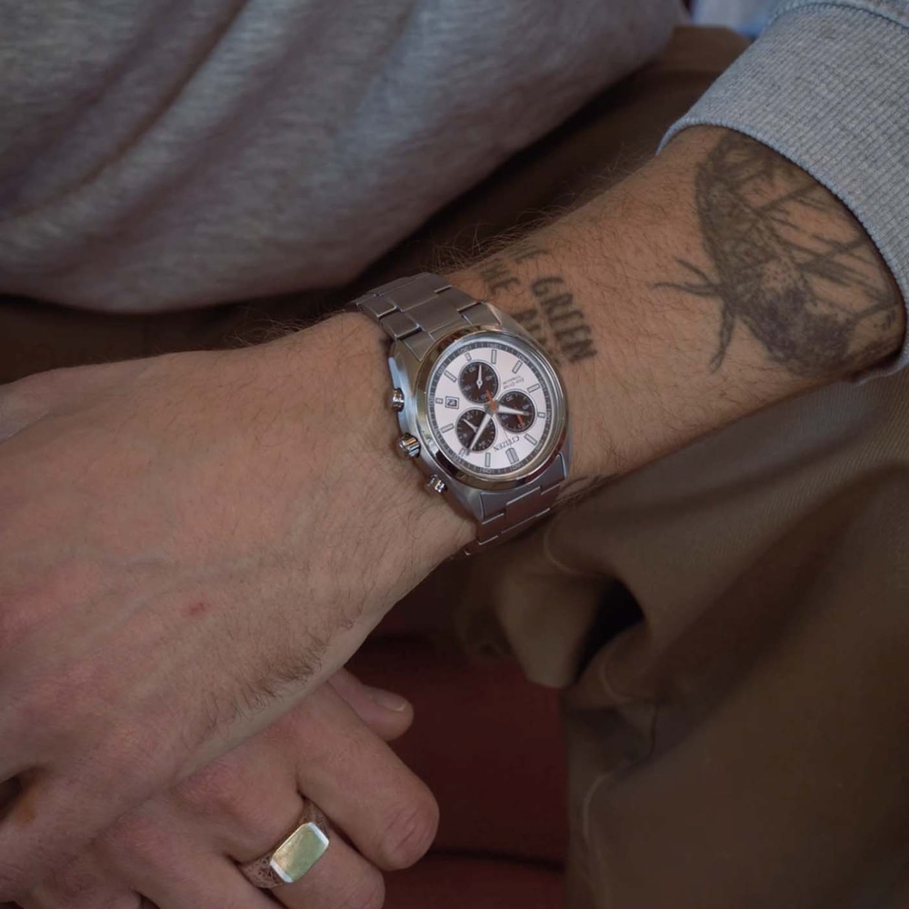 Een mannenpols met een horloge en een ring.