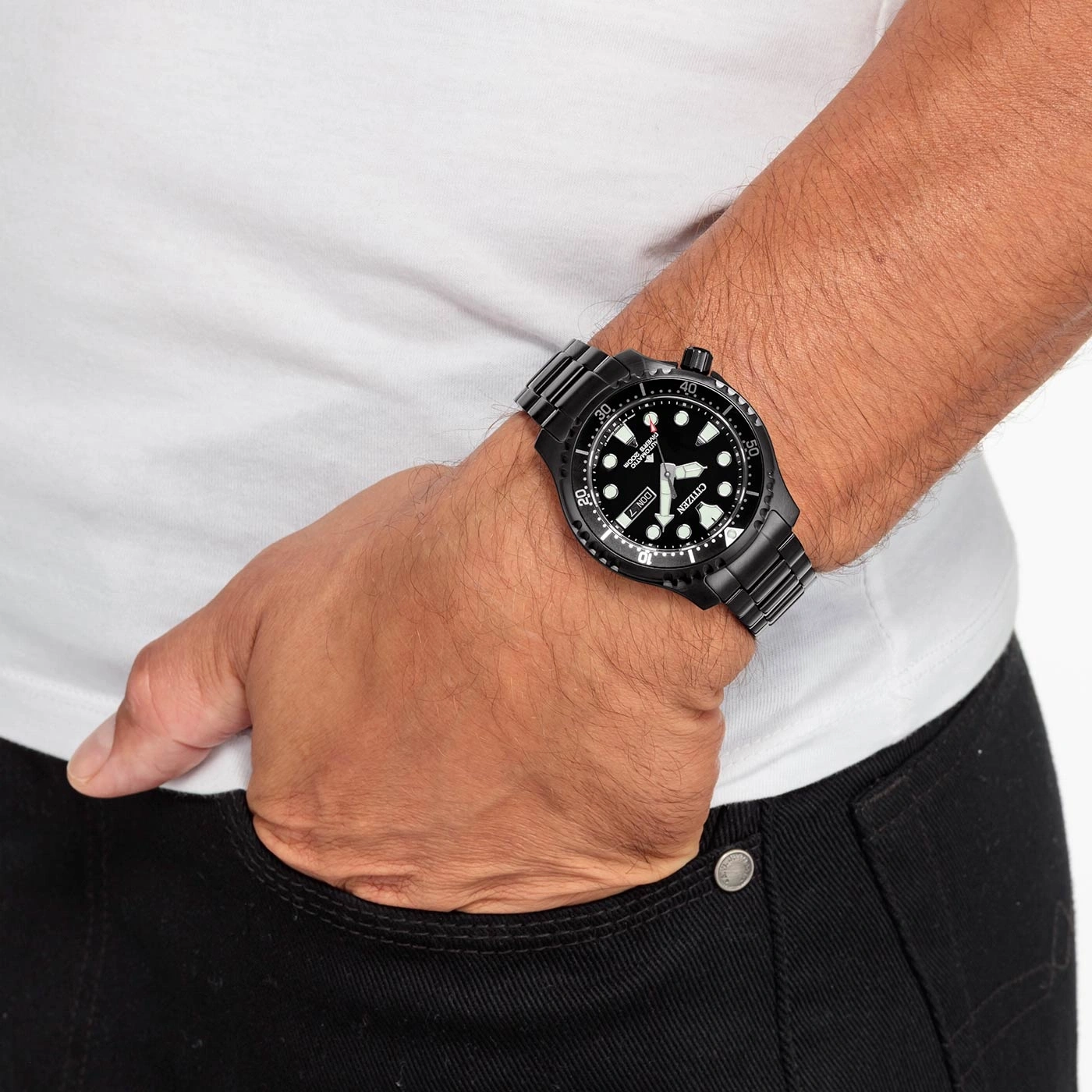 Man met zwart horloge, wit shirt en zwarte jeans. Detail van het horloge.