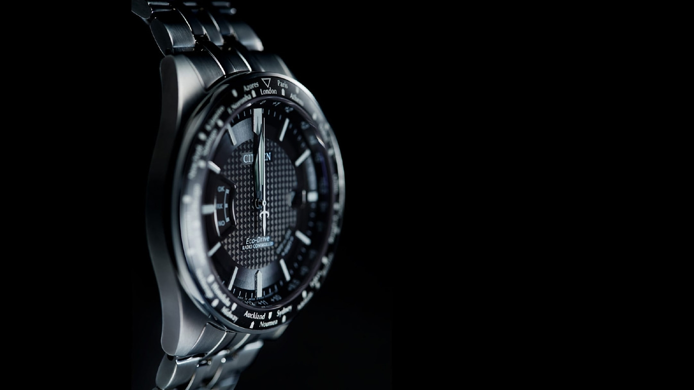 Close-up van een Citizen-horloge met zwarte wijzerplaat en zilveren band, tijdzones.