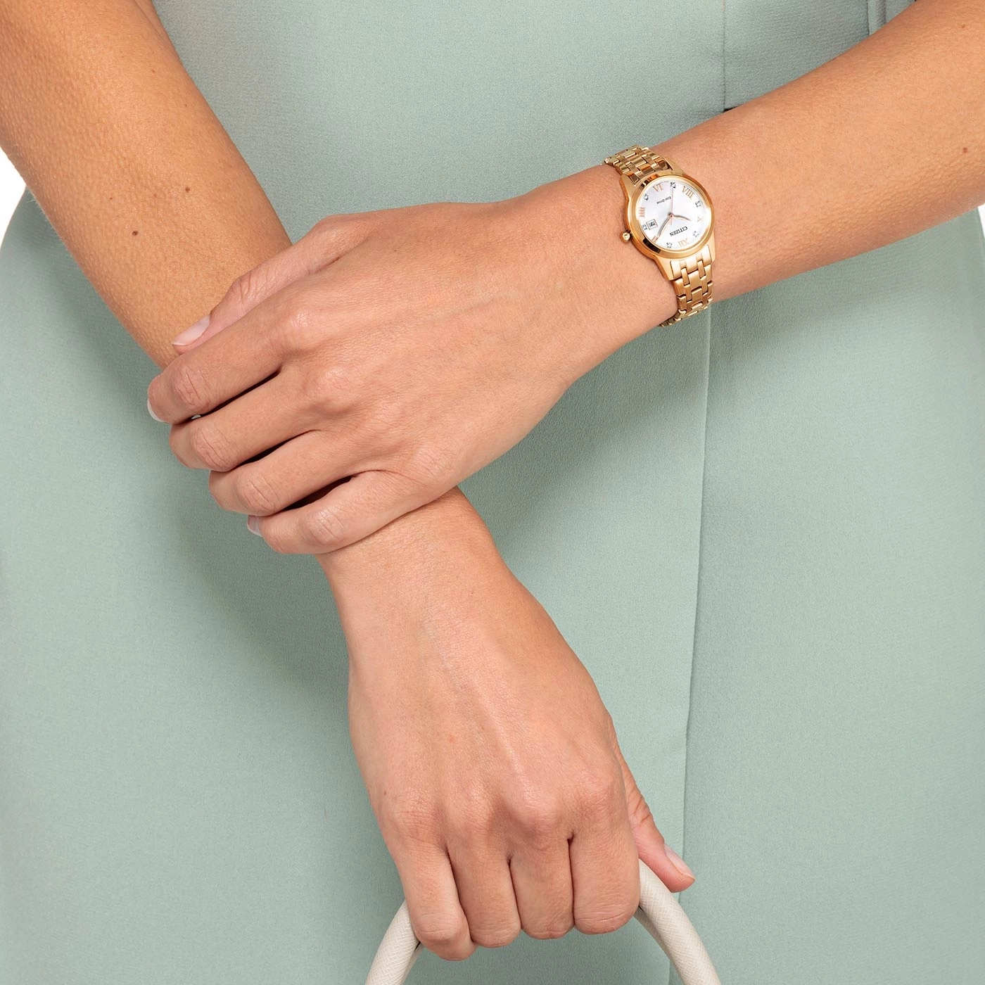Vrouw met gouden horloge, handtas, lichtgroene jurk, close-up handen