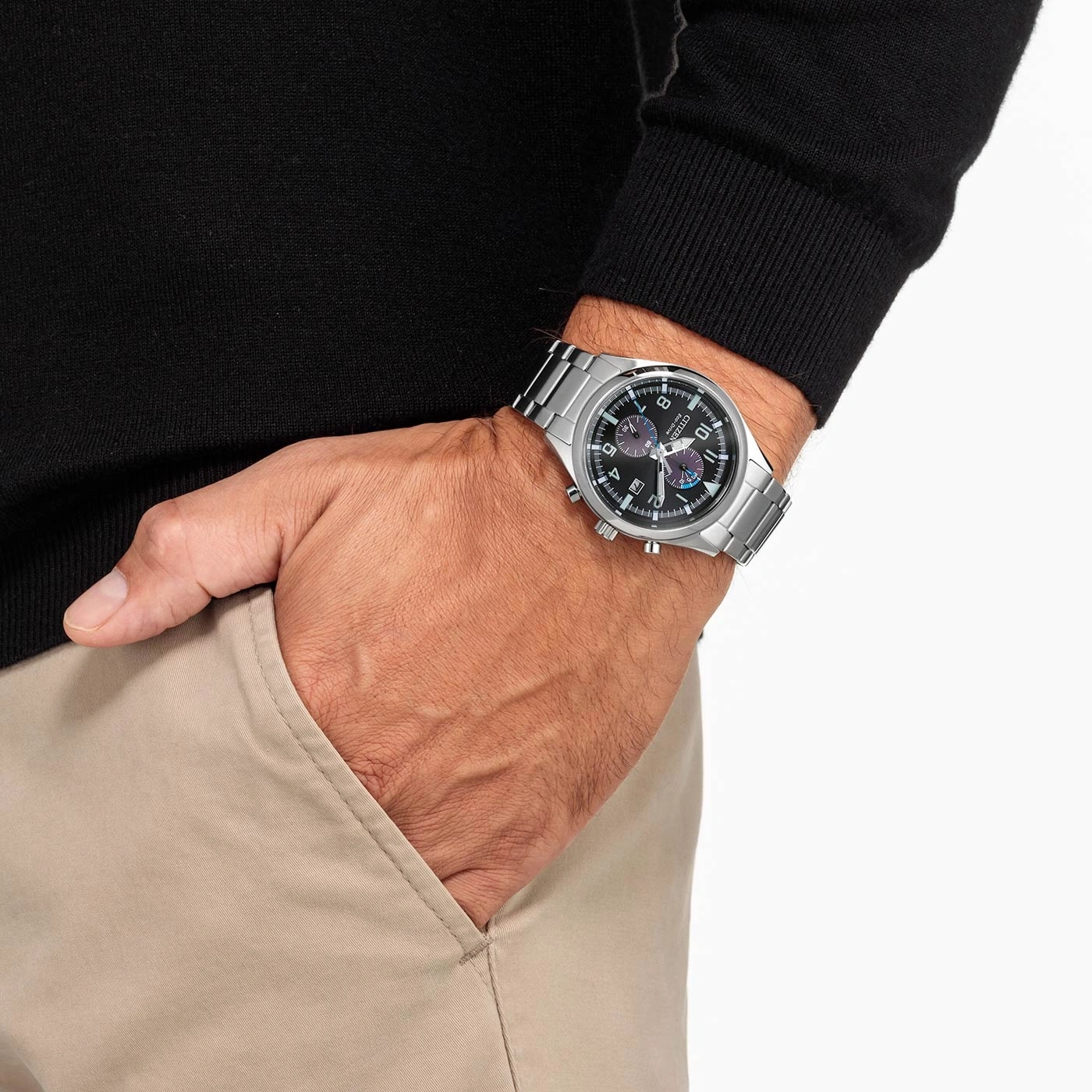 Man met zilveren horloge, zwarte trui en kaki broek.