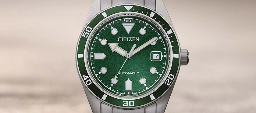 Close-up van een groene Citizen automatische horloge met datumvenster.