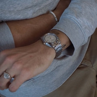 Close-up van een mannenarm met horloge en ring.
