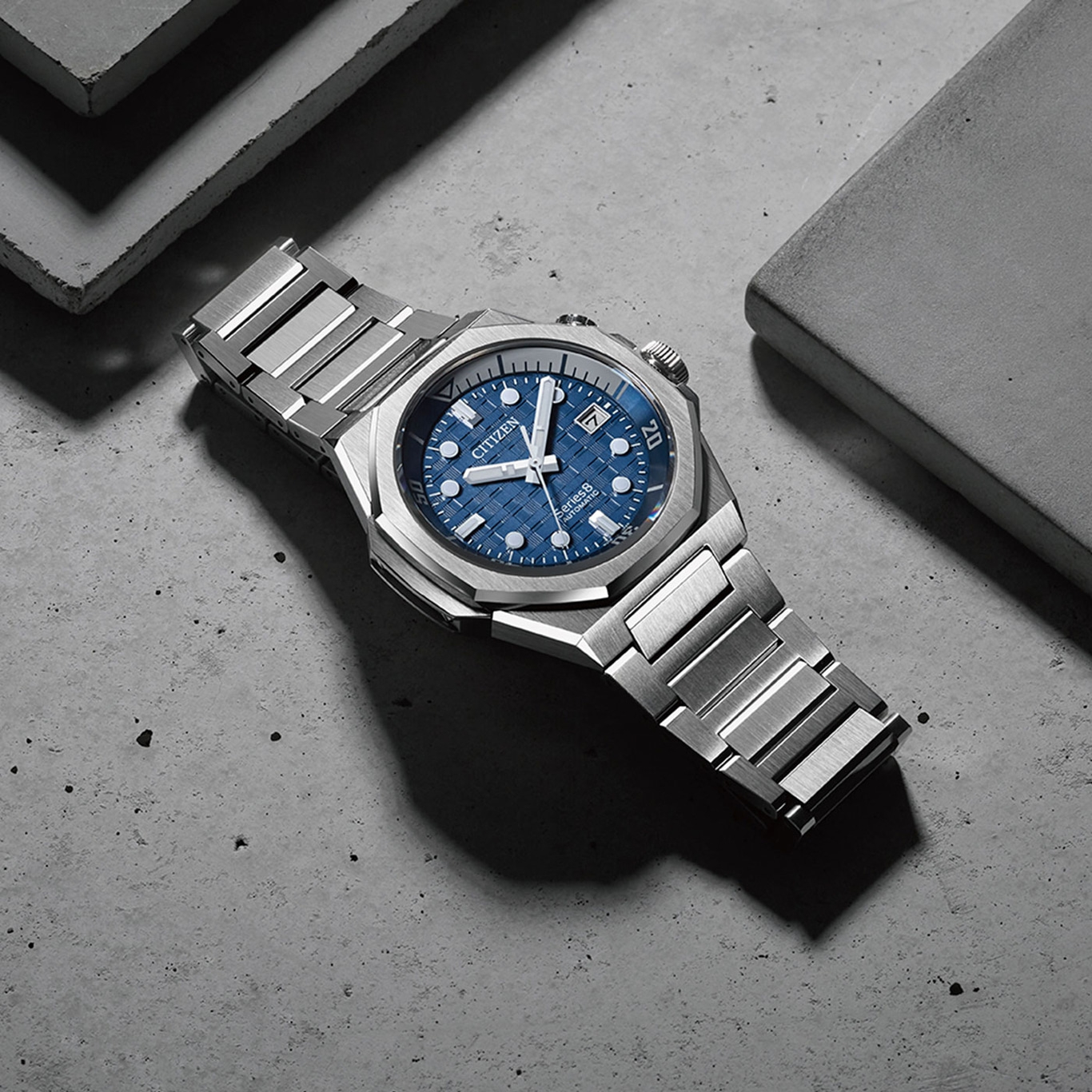 Citizen horloge met blauwe wijzerplaat en zilveren band op betonnen oppervlak