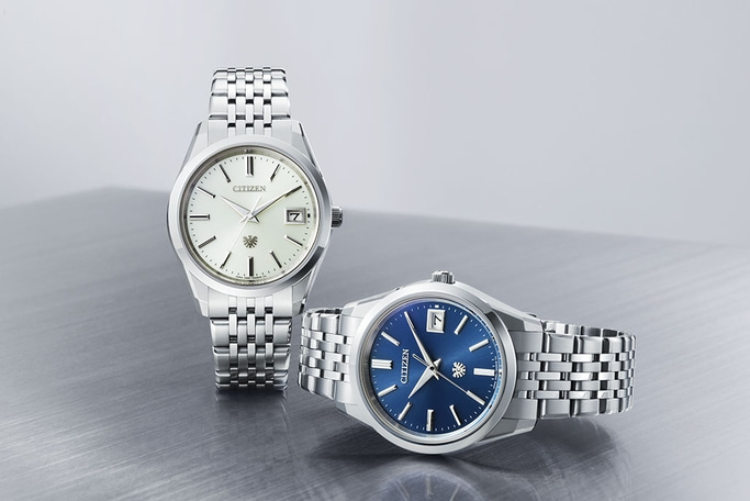 Twee Citizen horloges met zilveren bandjes en verschillend gekleurde wijzerplaten.