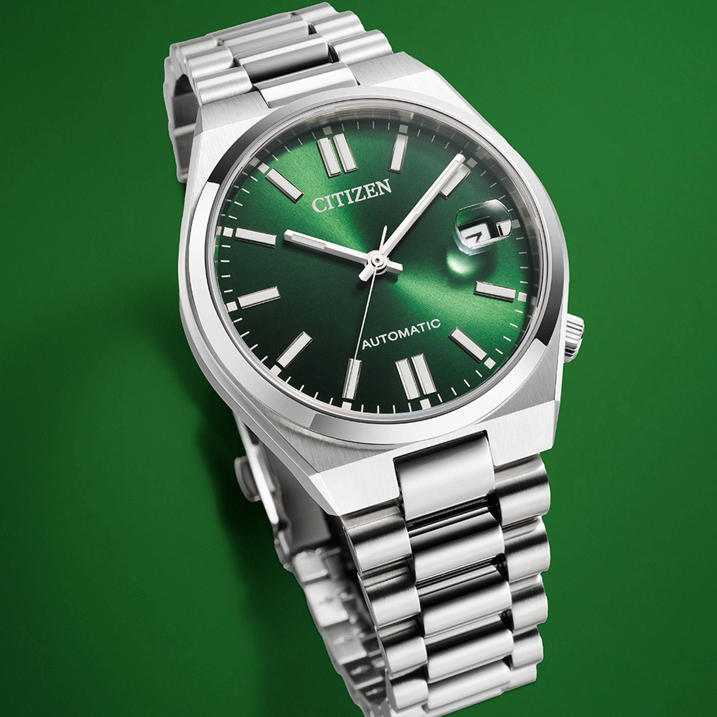 Citizen horloge met groene wijzerplaat en zilveren band op groene achtergrond.