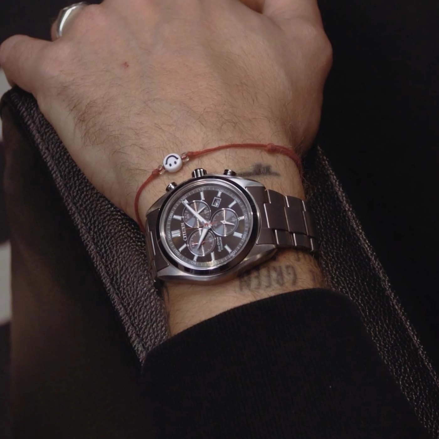 Mannelijke pols met horloge en smiley-armband.