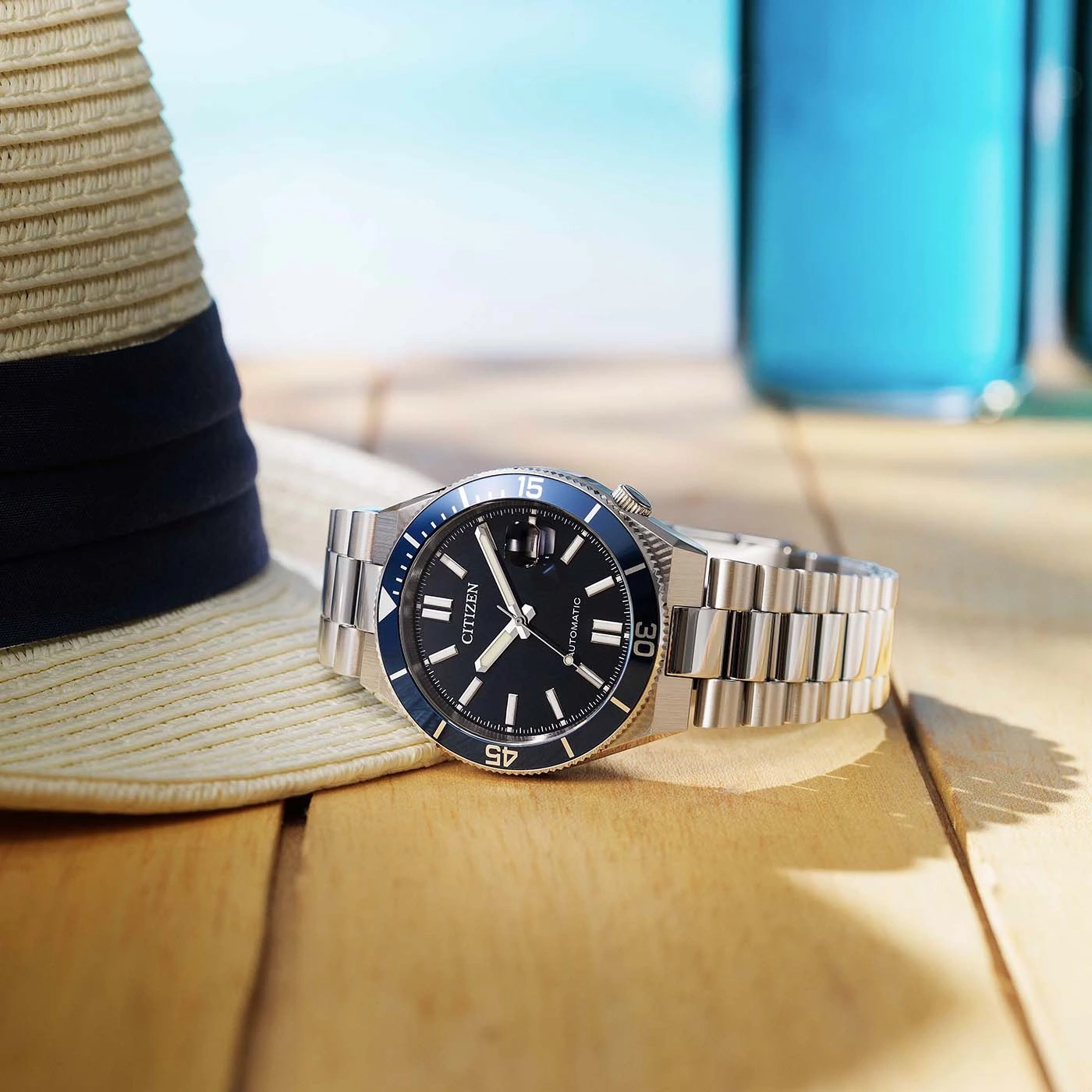 Een Citizen horloge op een houten tafel met een hoed en drankjes.