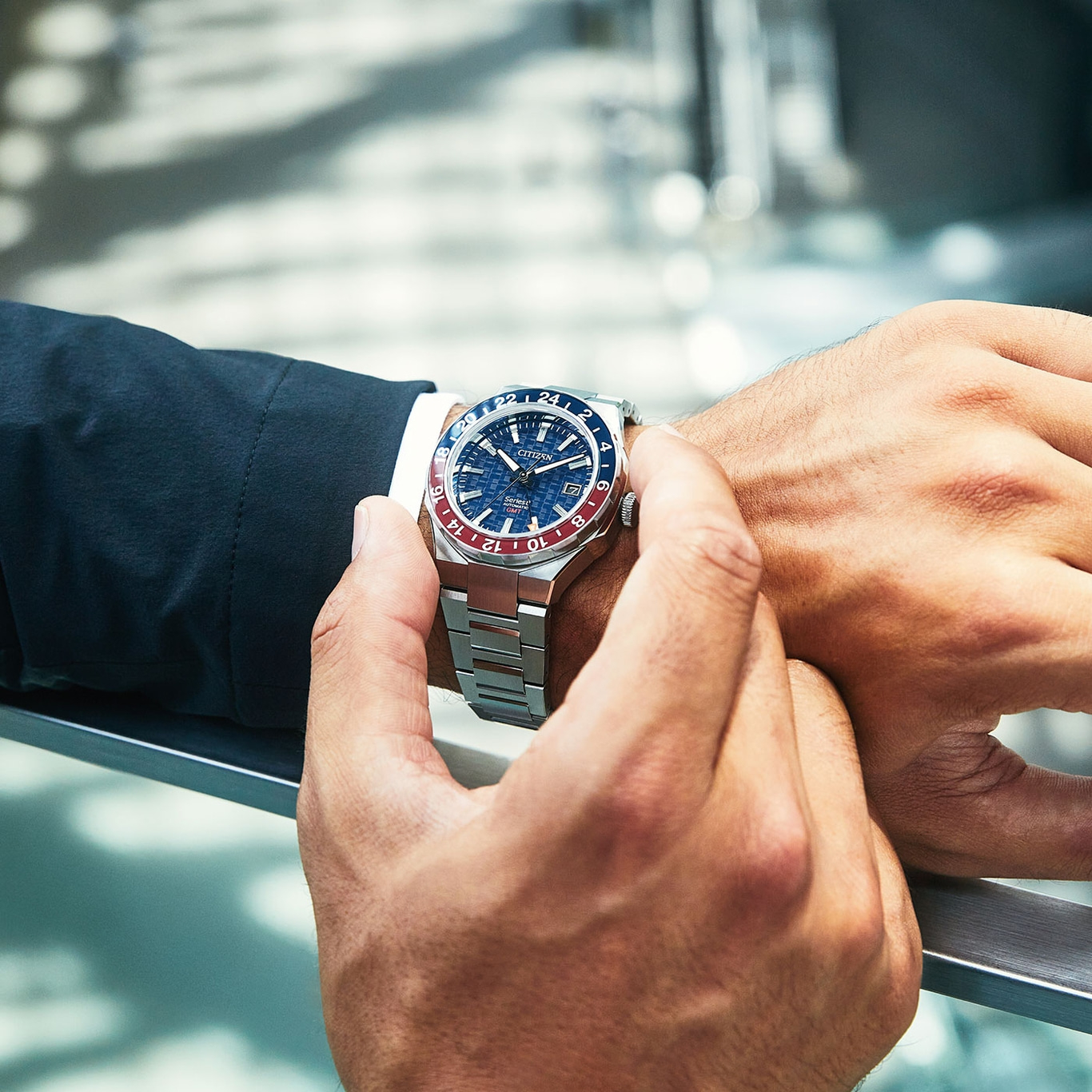 Nahaufnahme einer stilvollen Uhr mit blau-roter Lünette und Metallarmband.