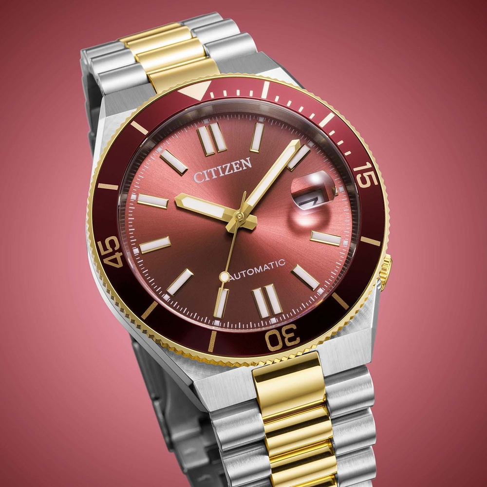 Close-up van een Citizen automatisch horloge met een rode wijzerplaat en gouden accenten.