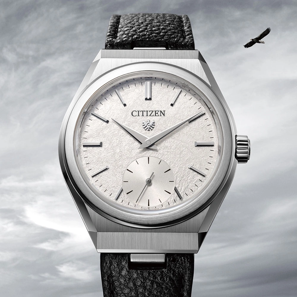 Citizen horloge met een getextureerde wijzerplaat en zwarte leren band, adelaar op de achtergrond.