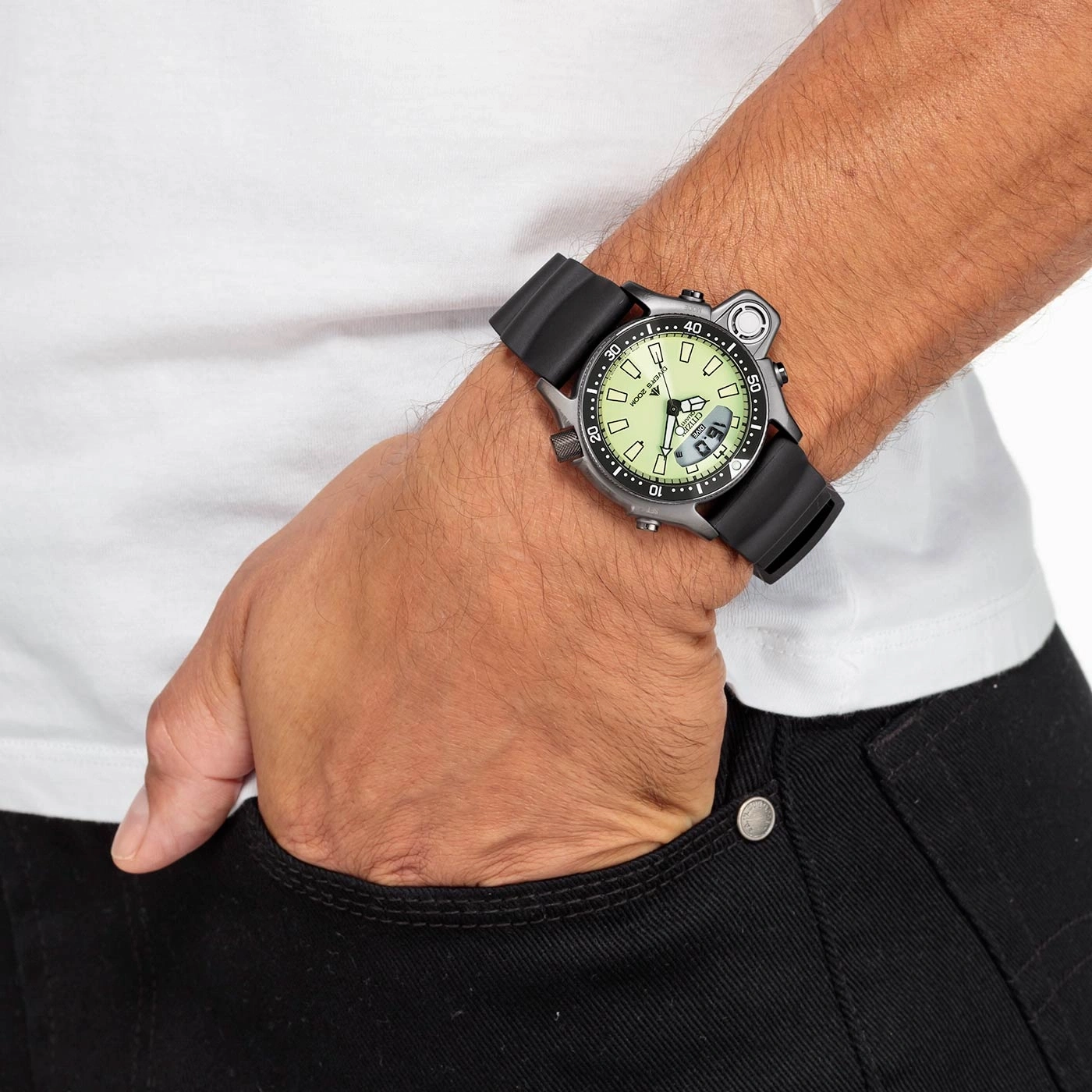 Man met horloge, hand in zak, zwarte jeans, wit shirt.