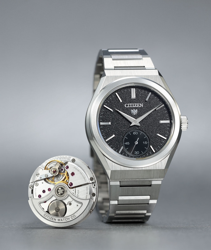 Citizen horloge met blootliggend mechanisme, zwarte wijzerplaat, zilveren armband en ingewikkelde details.