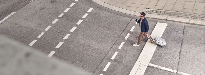 Man met koffer steekt de straat over bij een zebrapad