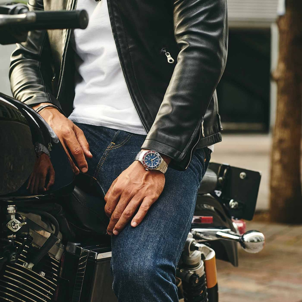 Man op motor met horloge, leren jas en jeans. Stoere uitstraling.