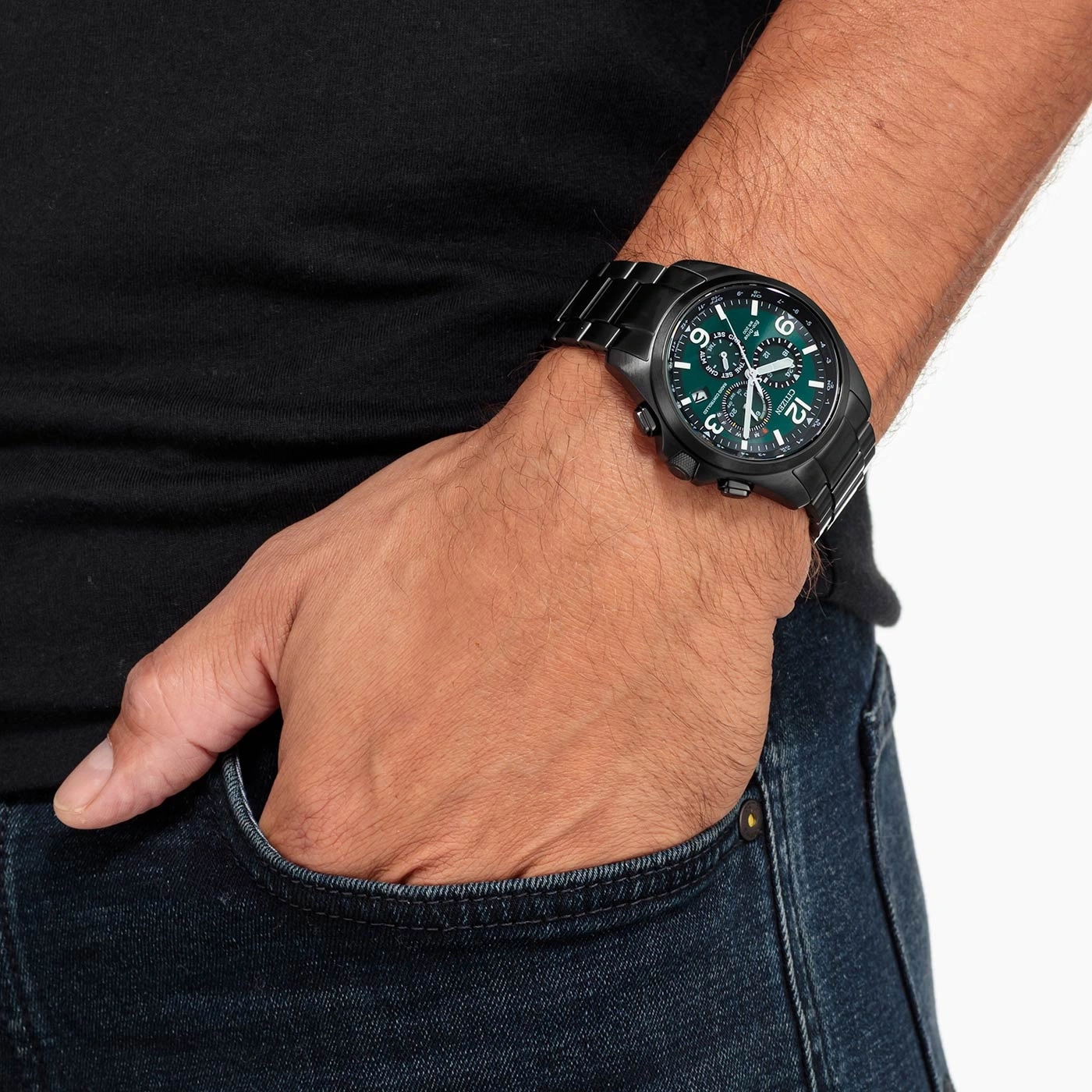Man met zwart horloge met groene wijzerplaat, hand in de zak.