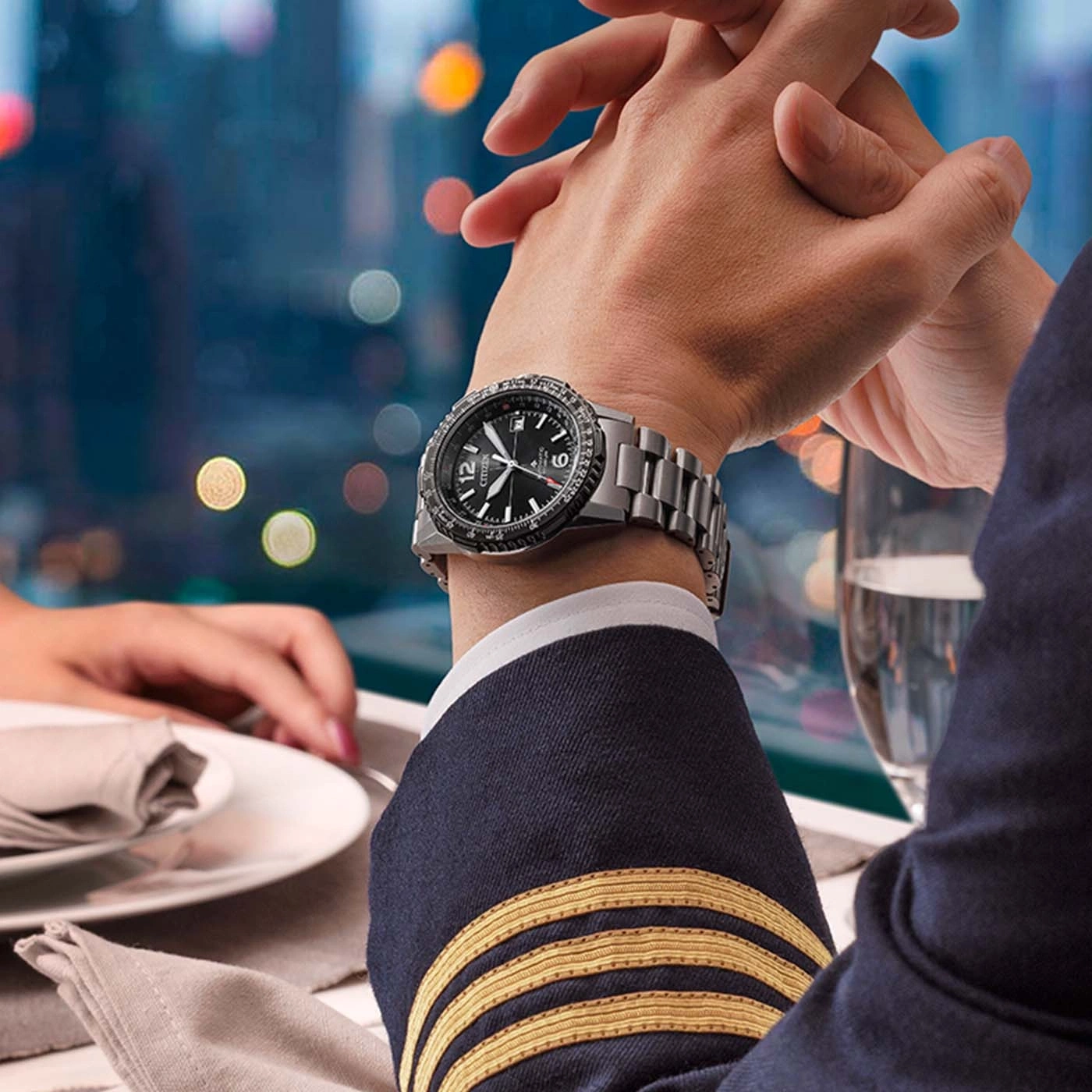 Man in pilotenuniform met horloge houdt handen vast