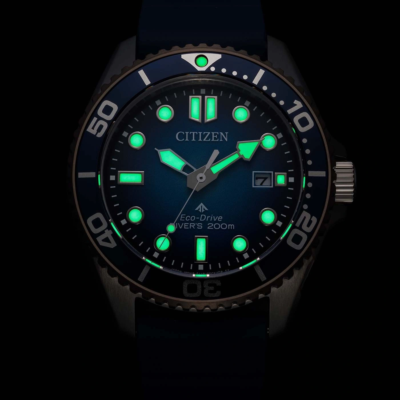 Close-up van een lichtgevend blauw Citizen Eco-Drive duikhorloge 's nachts, met gloeiende markeringen en wijzers.