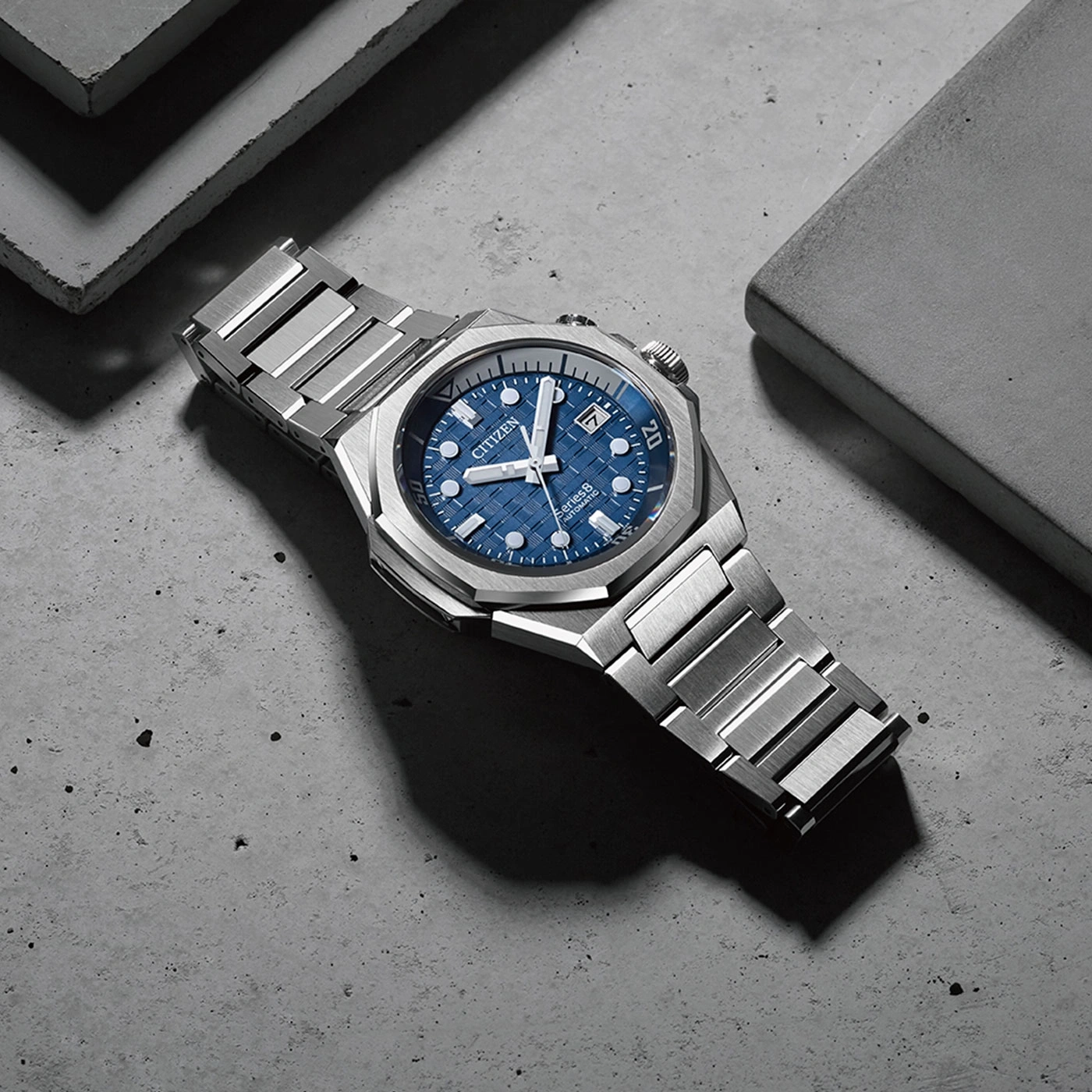 Citizen horloge met blauwe wijzerplaat en zilveren band op betonnen oppervlak