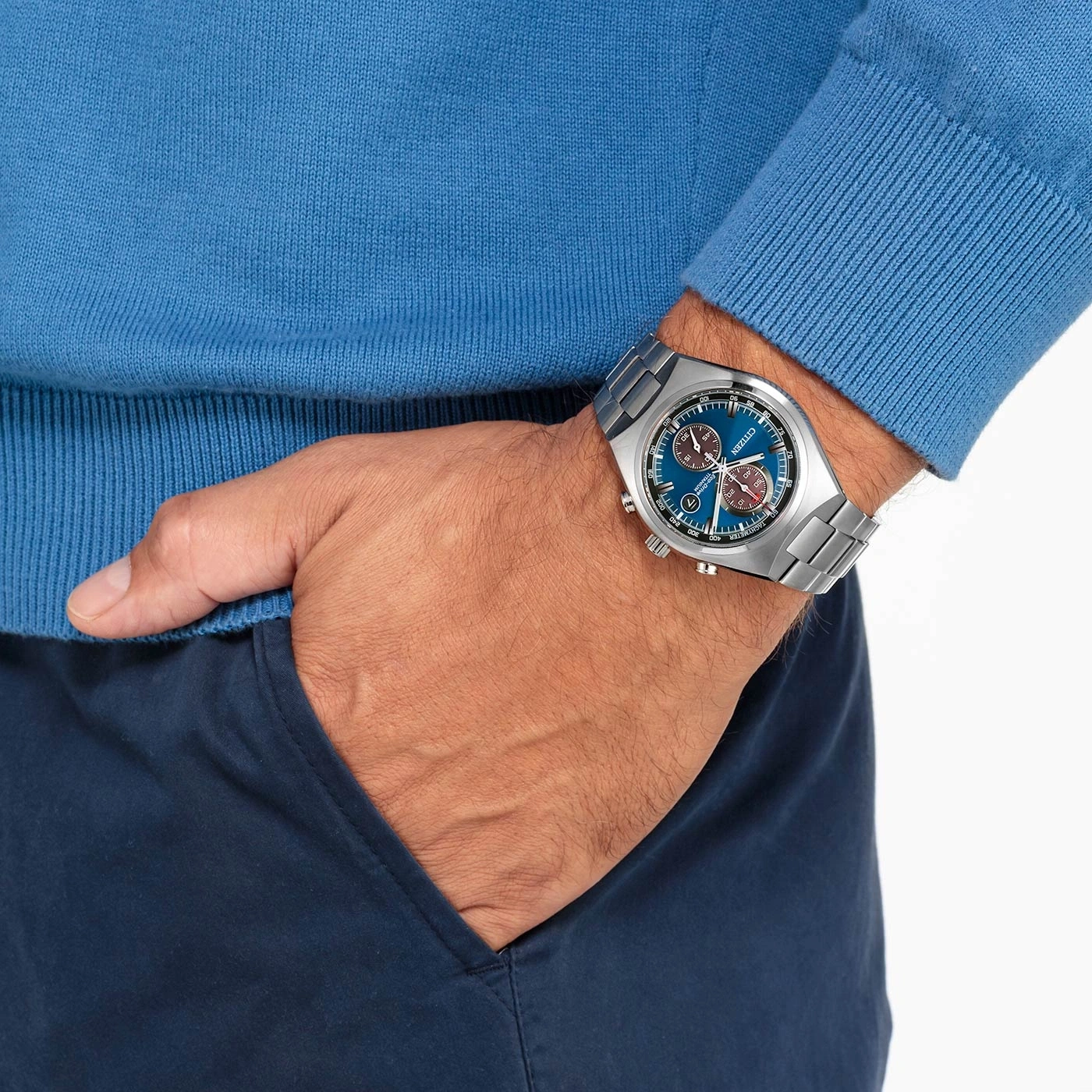 Man met blauw horloge, blauwe trui en blauwe broek, hand in de zak.