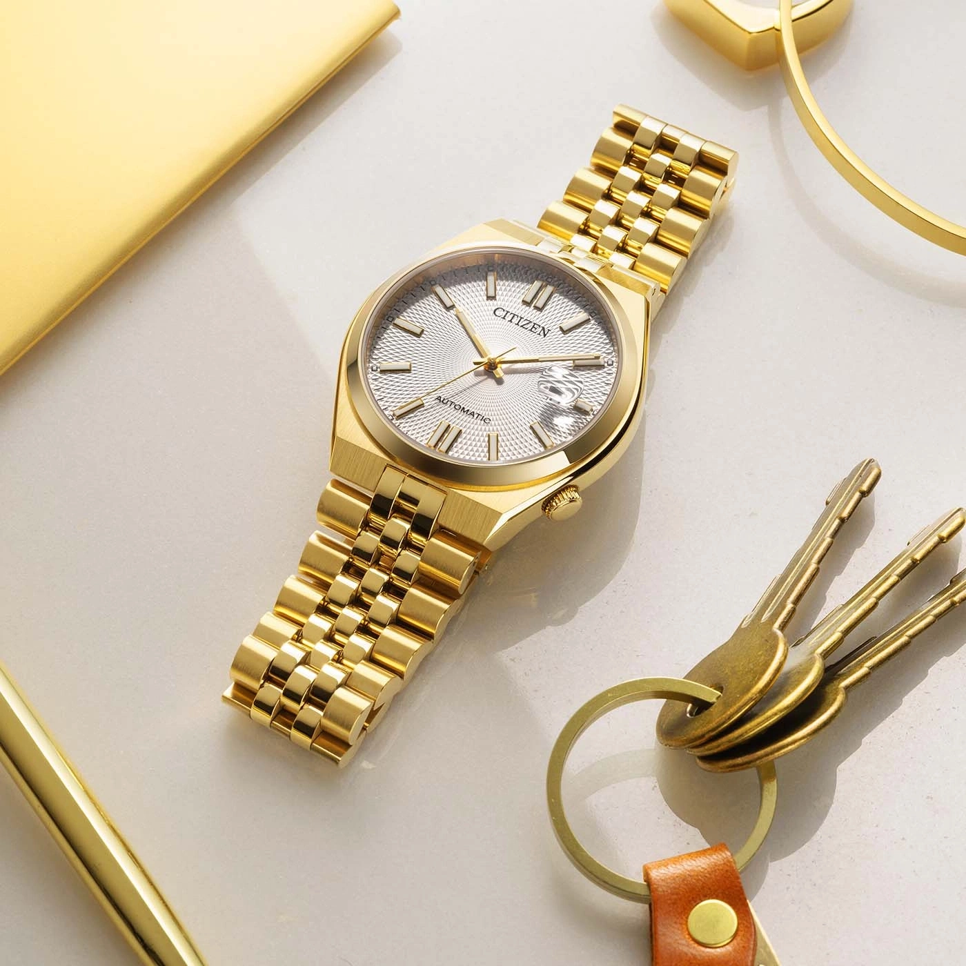 Een gouden Citizen automatische horloge met een getextureerd wijzerplaat en datumbereik.