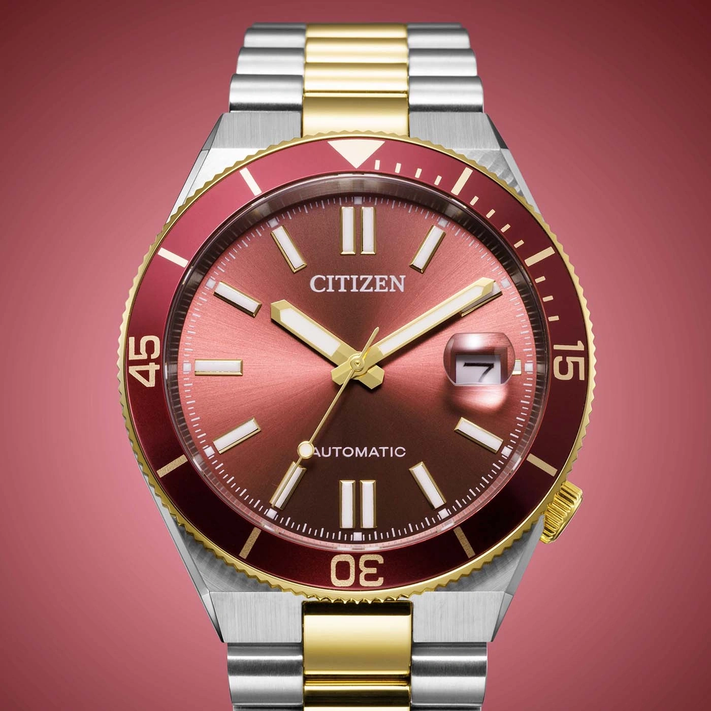 Close-up van een Citizen automatisch horloge met rode wijzerplaat en gouden accenten.