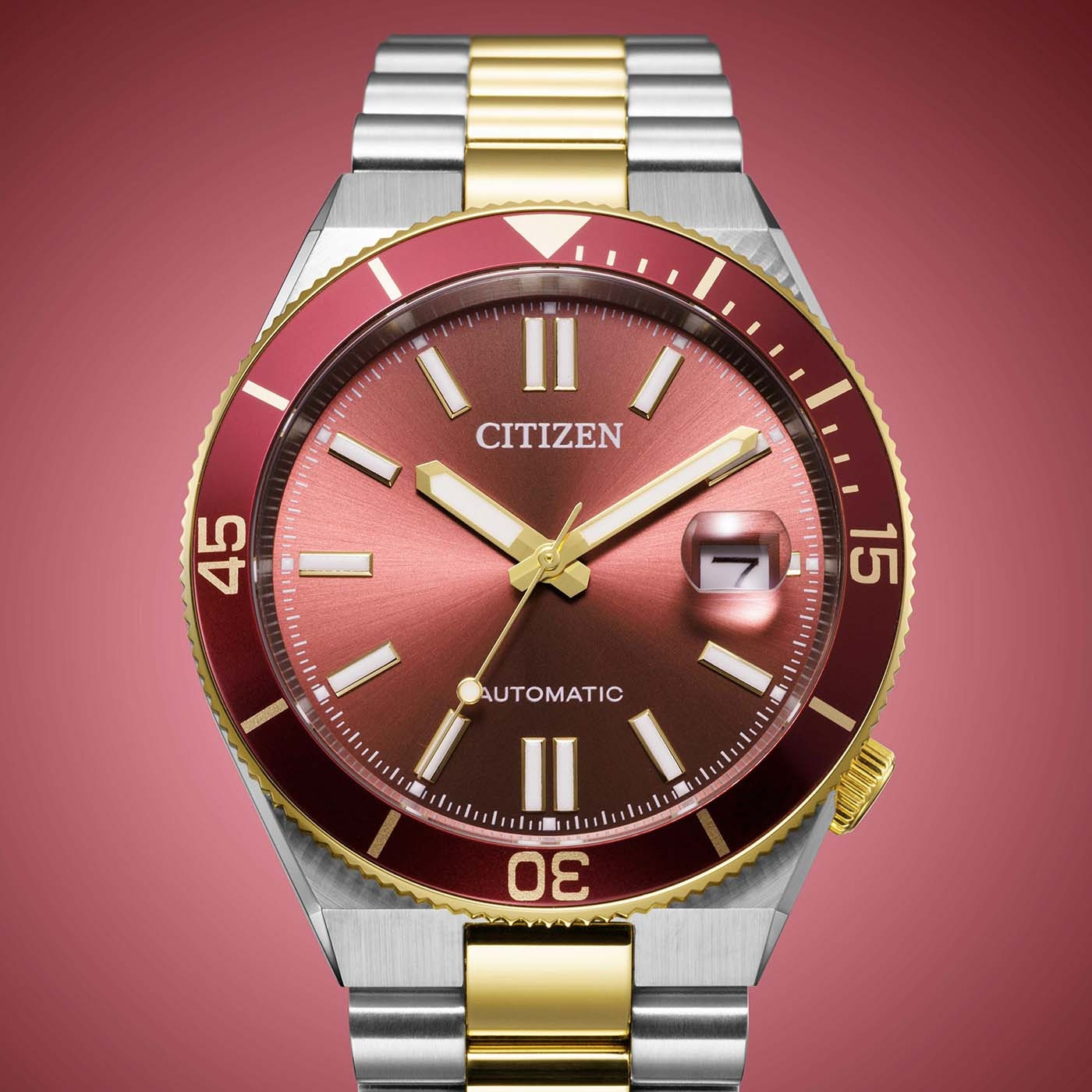 Close-up van een Citizen automatisch horloge met rode wijzerplaat en gouden accenten.