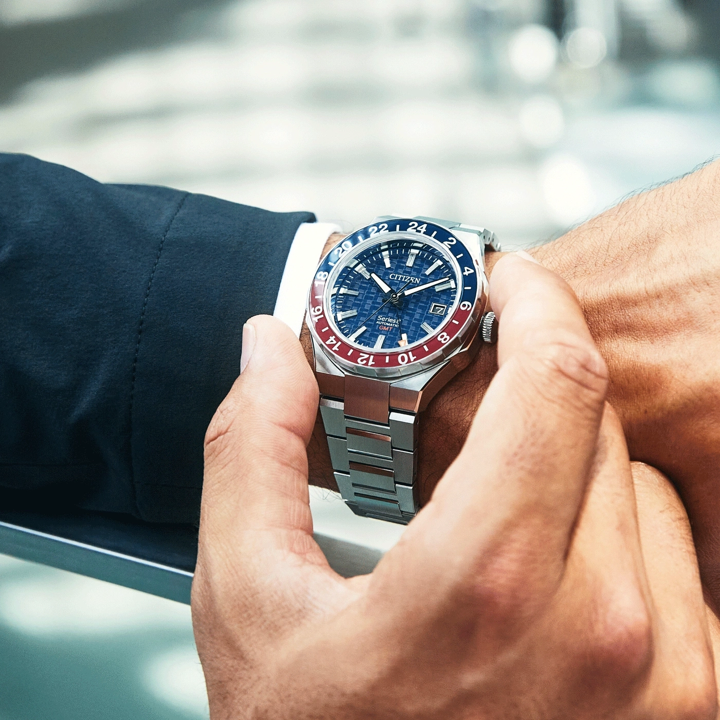 Man met een Citizen horloge. Blauwe en rode bezel. Roestvrijstalen armband.