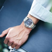 Man met zilveren horloge, houdt een donkerblauwe map vast.