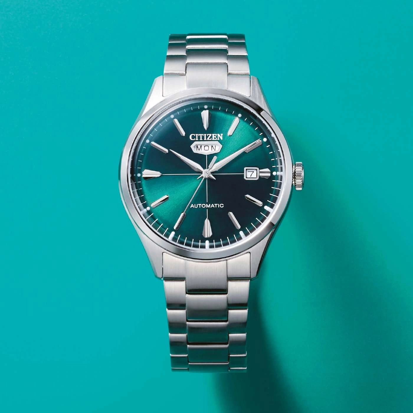 Een close-up, van bovenaf genomen foto van een zilverkleurig Citizen horloge met een groen wijzerplaat.