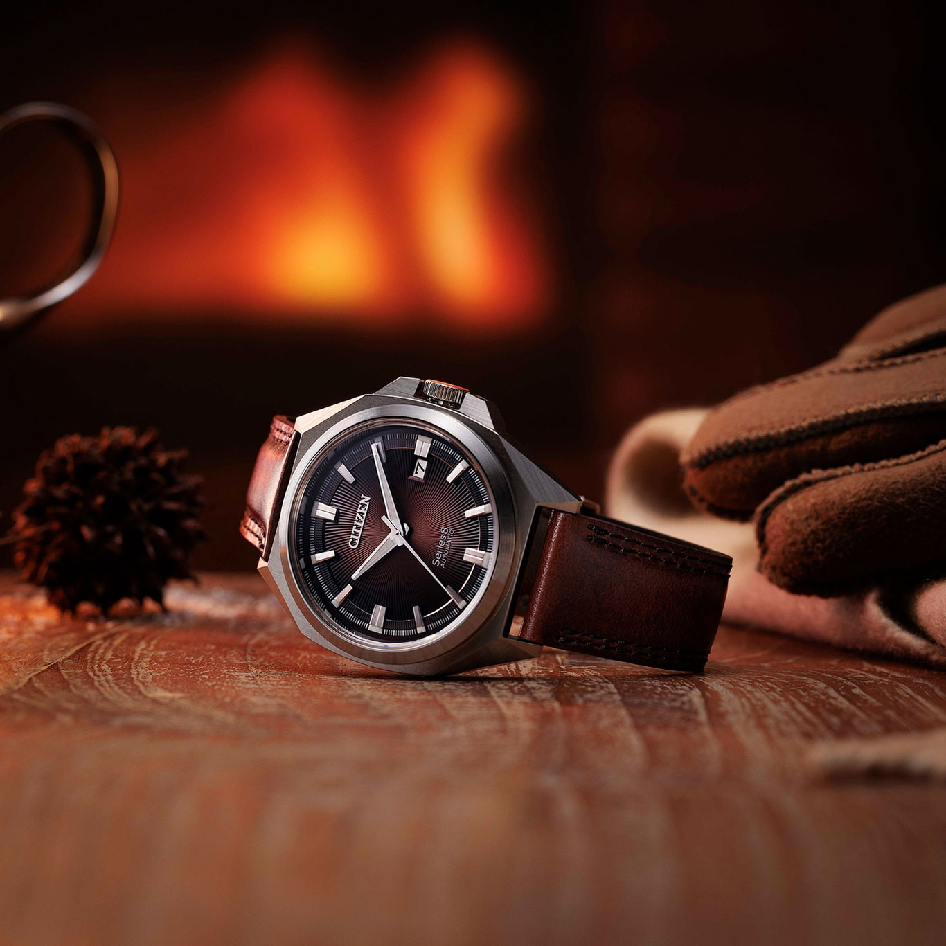 Citizen horloge op houten oppervlak met handschoenen en een vage achtergrond van een open haard.