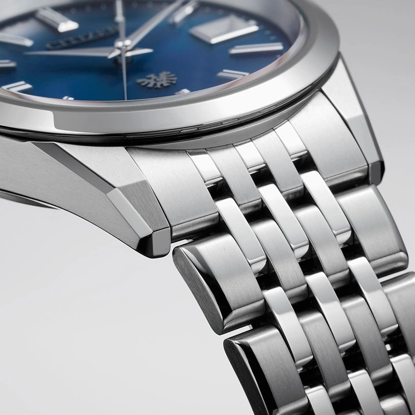 Close-up van een zilveren horloge met een blauwe wijzerplaat en metalen band.