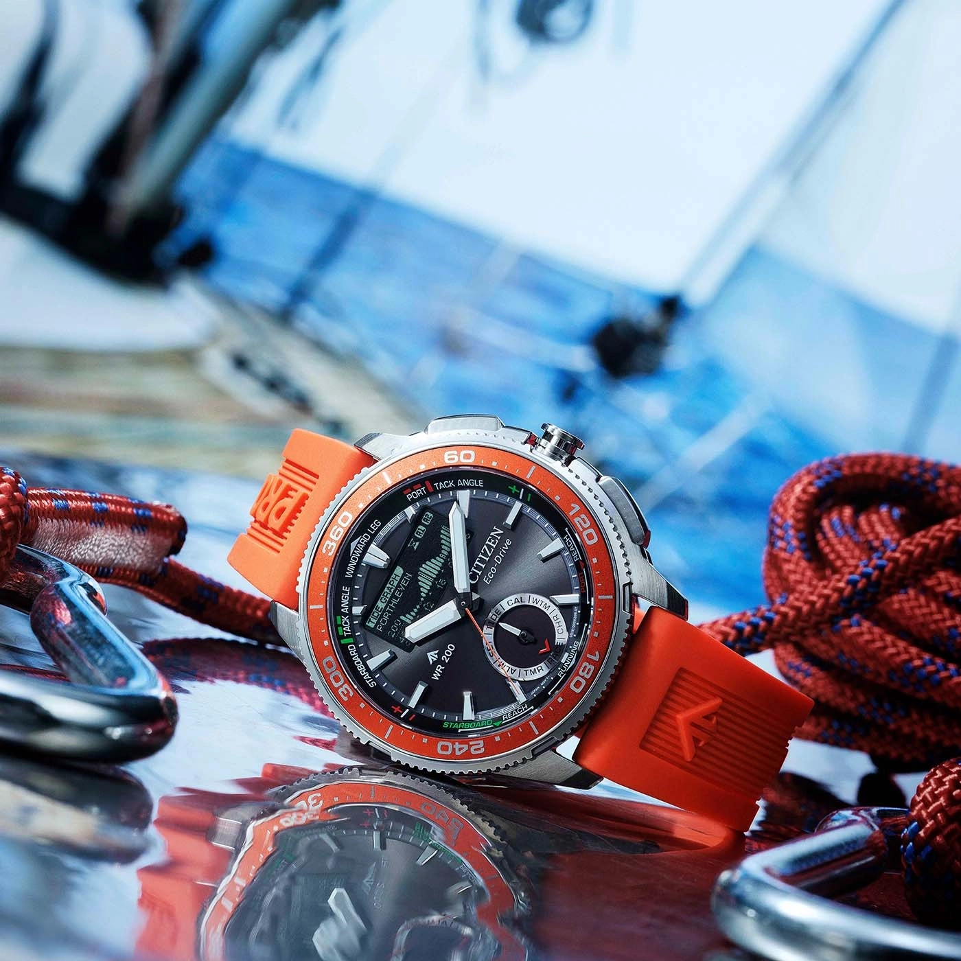 Een close-up van een Citizen Eco-Drive horloge met oranje band, omringd door zeiltouwen en karabiners.
