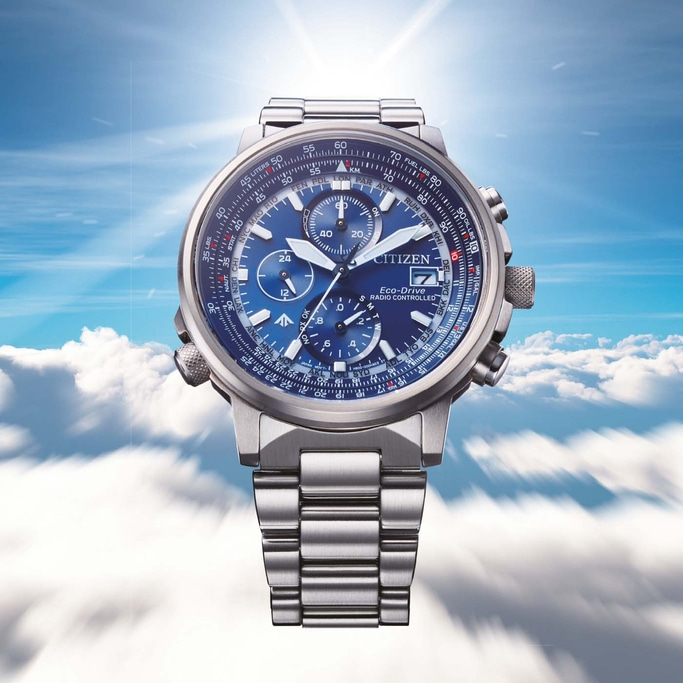 Citizen horloge met blauwe wijzerplaat, zilveren band en meerdere wijzerplaten tegen een bewolkte lucht.