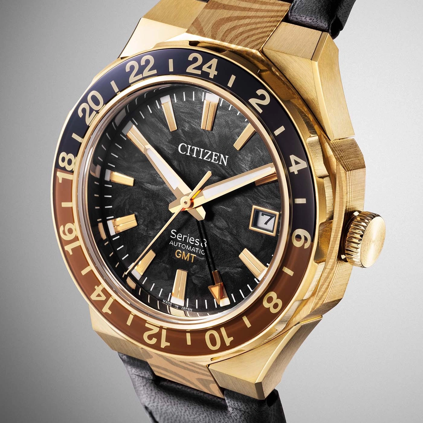 Een close-up van een luxe gouden Citizen GMT-horloge met een zwarte wijzerplaat en bruine accenten op de lunette.