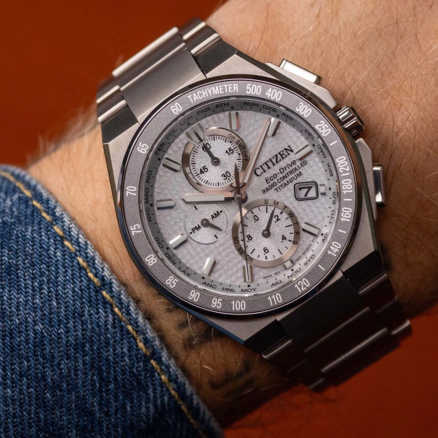 Close-up van een Citizen Eco-Drive Titanium horloge om de pols, met snelheidsmeter en wereldsteden.