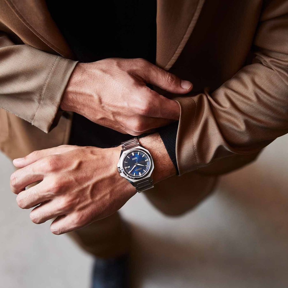 Man met horloge, handen op bruine jas, close-up