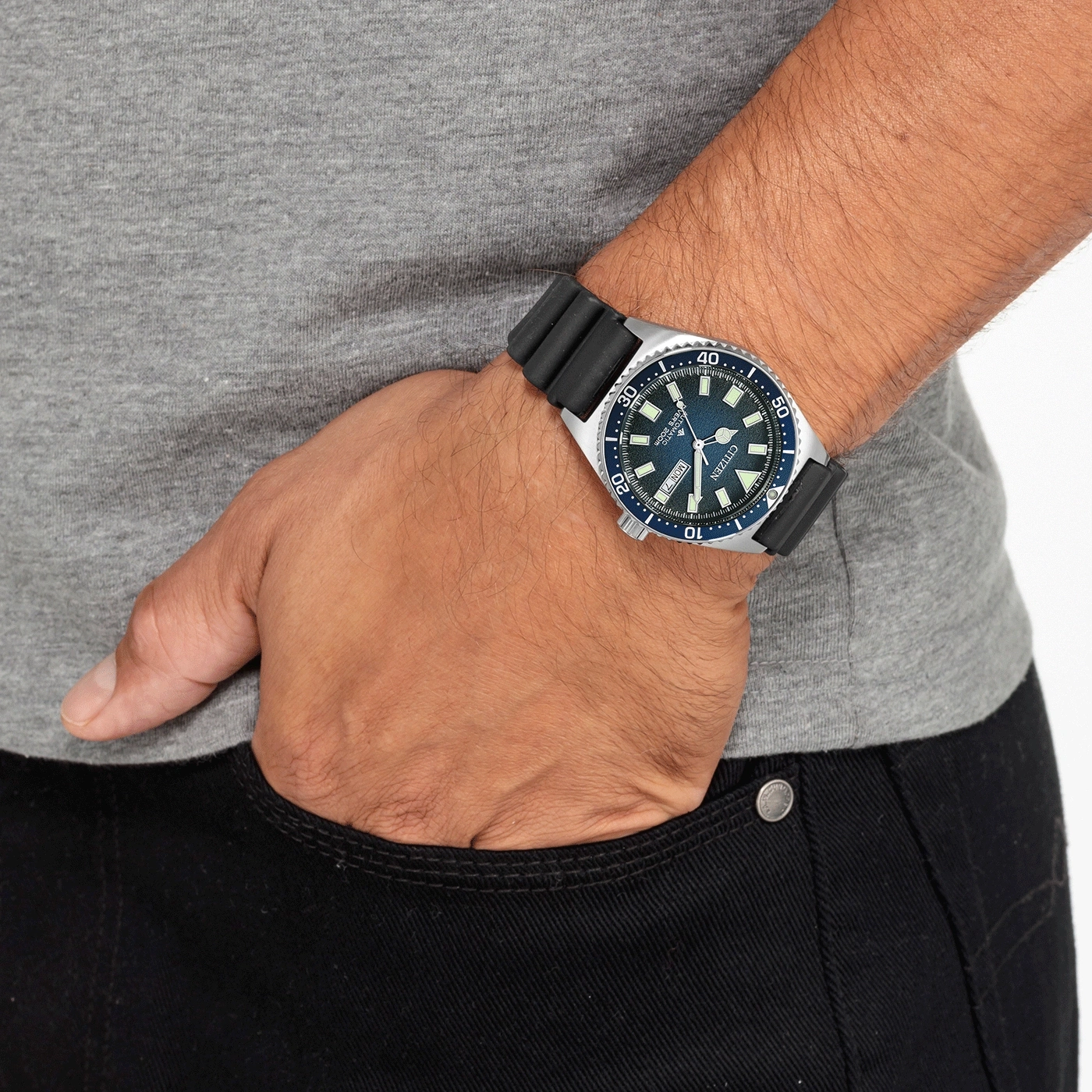 Man met Citizen horloge, hand in zak, grijs shirt, zwarte jeans.