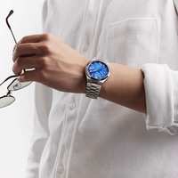 Man in wit shirt met blauw horloge, houdt bril vast.
