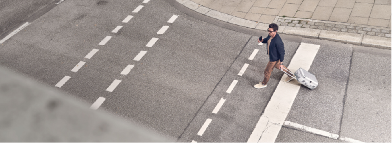 Man met koffer steekt de straat over bij een zebrapad