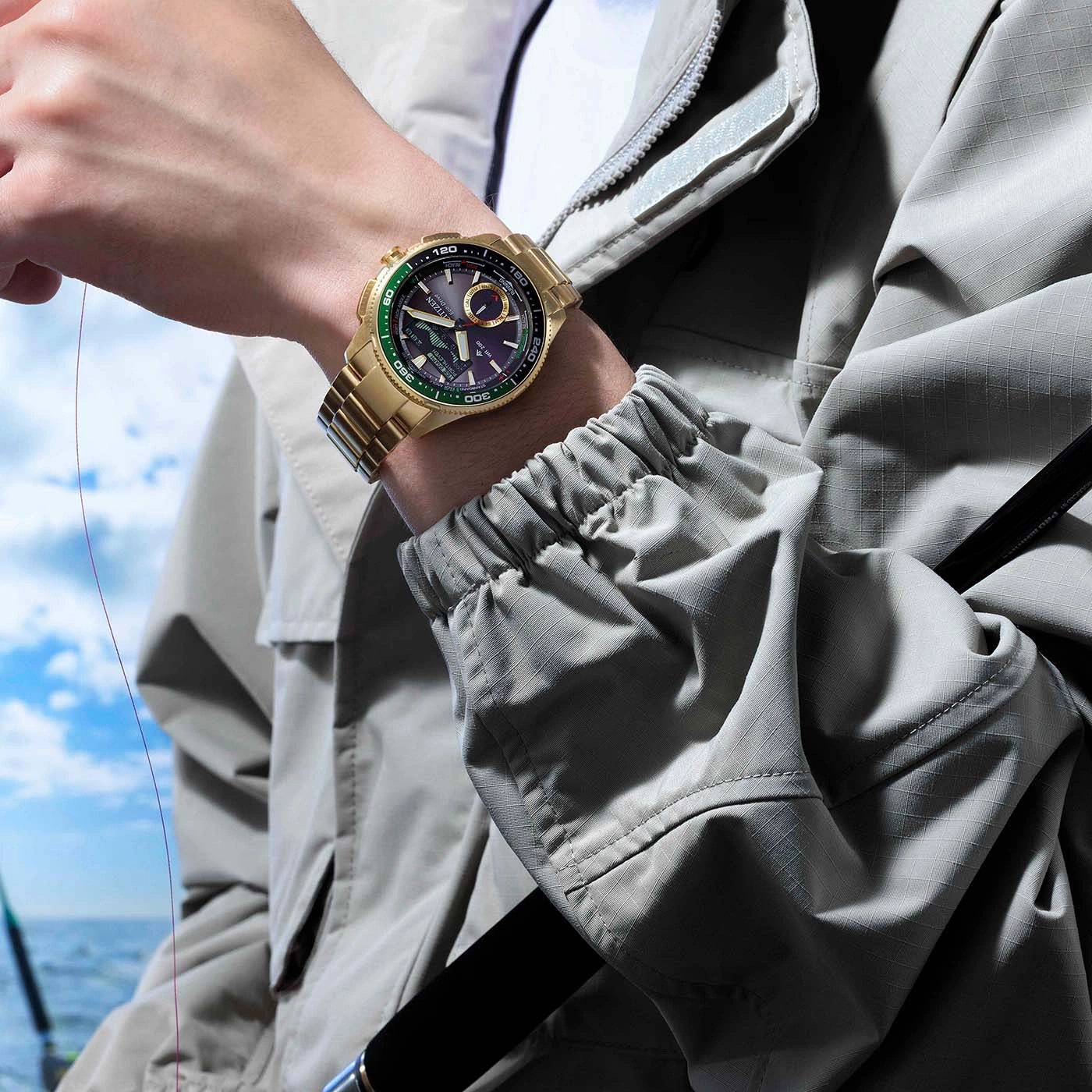 Gouden horloge om de pols van een man, vishengel op de achtergrond.