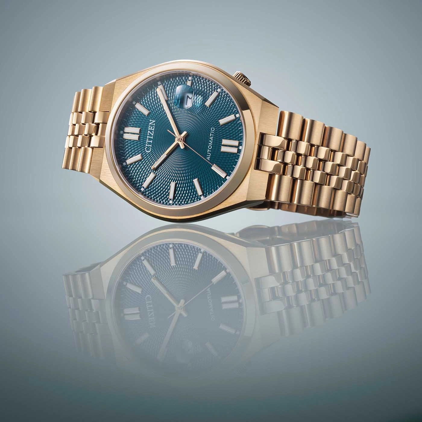 Gouden Citizen horloge met blauwe wijzerplaat en reflectie op een oppervlak.