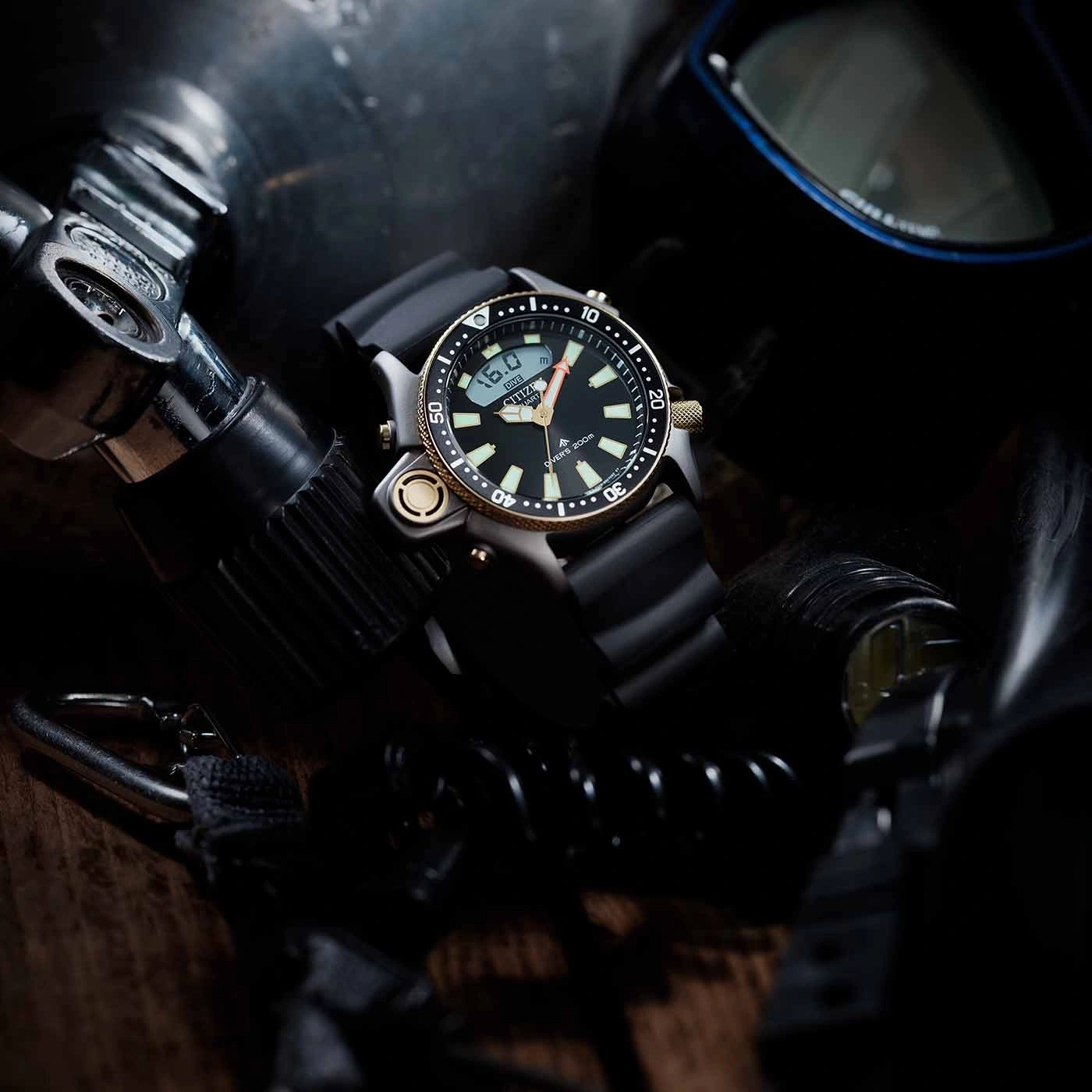 Close-up van een duikhorloge met duikuitrusting op de achtergrond.