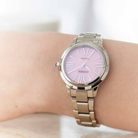 Een close-up van een Citizen horloge om een pols, roze wijzerplaat, zilveren band.