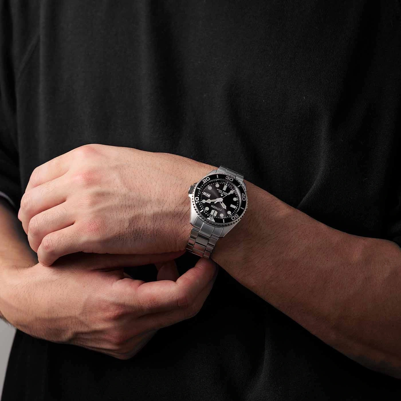 Man draagt een zilveren horloge met een zwarte wijzerplaat om zijn pols