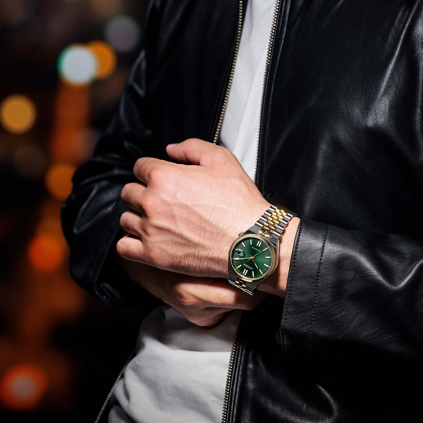 Man met horloge met groene wijzerplaat en gouden en zilveren band