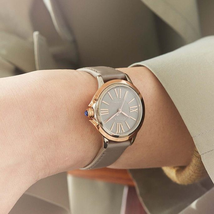 Close-up van een Citizen horloge om een pols, met een grijze band en roségouden accenten.