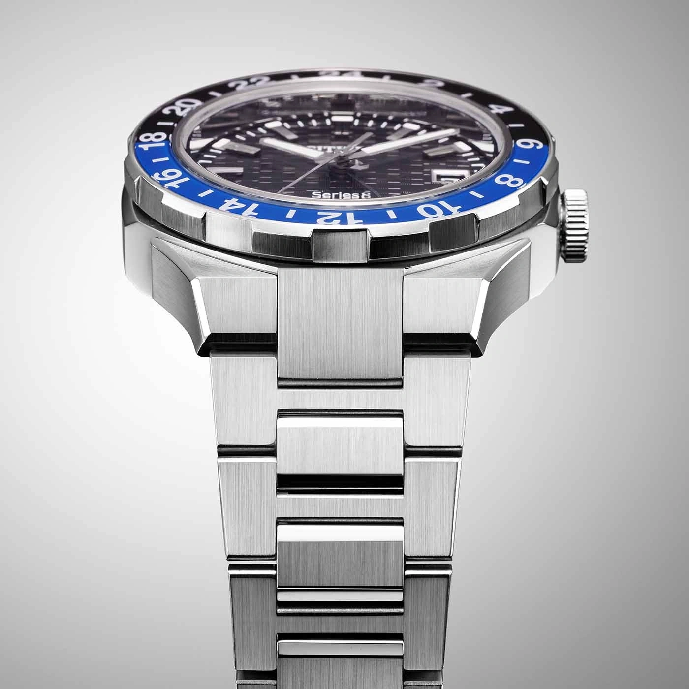 Close-up van een zilveren horloge met een blauw-zwarte bezel en een metalen band.