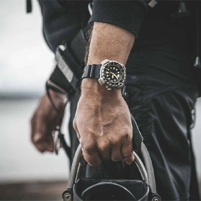Man met horloge, houdt apparatuur vast, close-up, zwarte outfit, buiten